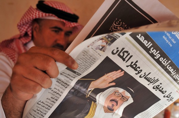 A Saudi man reads a newspaper with a fro