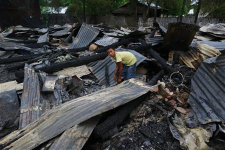 A boy salvages belongings amid burnt debris at Htan Kone village in Myanmar's northern Sagaing