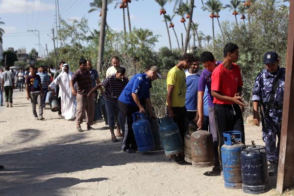 Palestinians wait to fill a cooking gas canister in station in Dir al-Balah