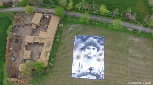 Artists install massive poster of child’s face in Pakistan field to shame drone operators