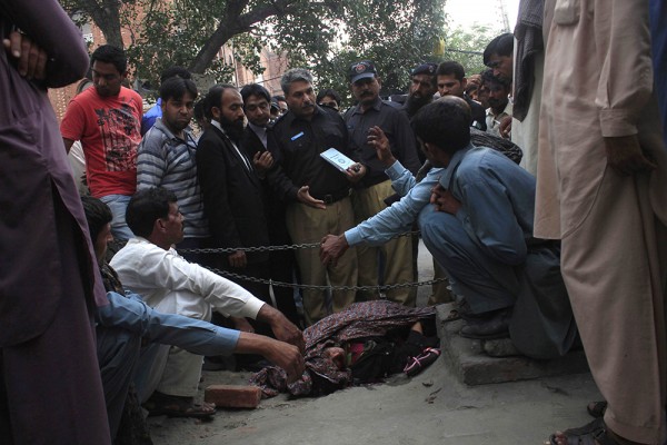 Police collect evidence near body of Farzana Iqbal, killed by family members, at site near Lahore High Court building in Lahore