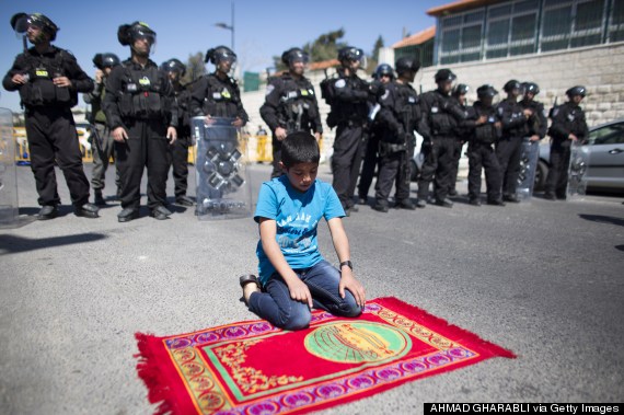 This inspiring picture by Ahmad Gharabli captures a Palestinian child praying to Allah in the presence of his oppressors. 