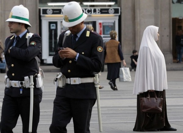 Muslim woman passes two Italian police officers in Milan