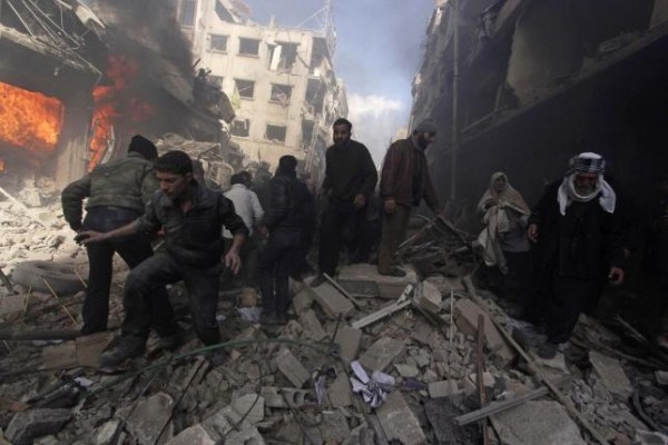 People walk on rubble as others try to put out a fire after what activists said were airstrikes and shelling by forces loyal to Syria's President Assad in Douma