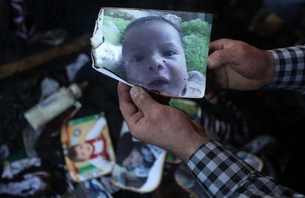 A man shows a picture of 18-month-old Palestinian toddler Ali Saad Dawabsha who died when his family house was set on fire by Jewish settlers in the West Bank village of Duma on July 31, 2015. The Palestinian toddler was burned to death and four family members injured in the arson attack on two homes in the occupied West Bank. AFP PHOTO / JAAFAR ASHTIYEH