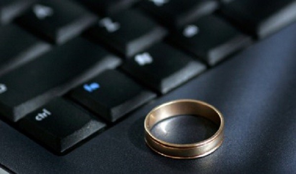 A wedding ring sits on a laptop keyboard