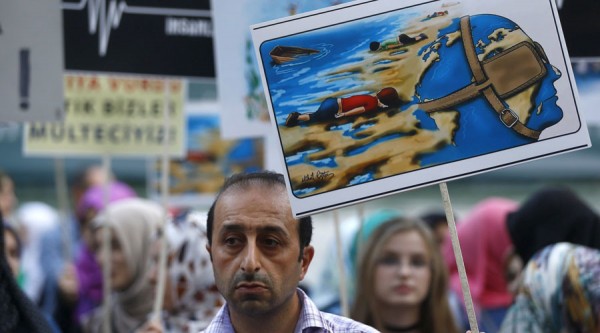 A man holds a poster with a drawing depicting drowned Syrian toddlers during a demonstration for refugee rights in Istanbul, Turkey, September 3, 2015. The distraught father of two Syrian toddlers who drowned with their mother and several other migrants as they tried to reach Greece identified their bodies on Thursday and prepared to take them back to their home town of Kobani. Abdullah Kurdi collapsed in tears after emerging from a morgue in the city of Mugla near Bodrum, where the body of his three-year old son Aylan washed up on Wednesday. The image of Aylan, drowned off one of Turkey's most popular holiday resorts, went viral on social media and piled pressure on European leaders. Abdullah's family had been trying to emigrate to Canada after fleeing the war-torn town of Kobani, a revelation which also put Canada's Conservative government under fire from its political opponents. REUTERS/Osman Orsal - RTX1QZ0X