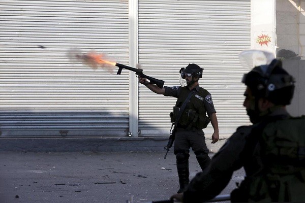 An Israeli border policeman fires tear gas towards Palestinian protesters during clashes at a checkpoint between Shuafat refugee camp and Jerusalem October 9, 2015. REUTERS/Ammar Awad