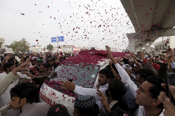 Supports shower a hearse carry Qadri with rose petals.