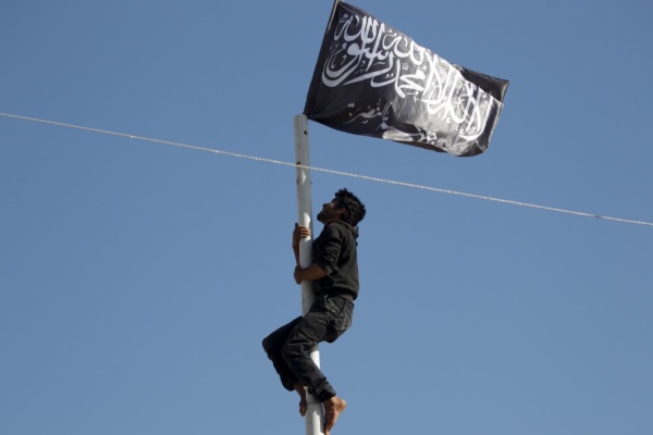 A member of al Qaeda's Nusra Front climbs a pole where a Nusra flag was raised at a central square in the northwestern city of Ariha, after a coalition of insurgent groups seized the area in Idlib province May 29, 2015. A Syrian insurgent alliance which has captured the last government-held town in the northwestern Idlib province made further advances on Friday, a monitoring group and fighters said. REUTERS/Khalil Ashawi  - RTR4Y10S