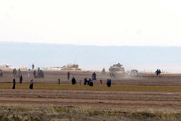 Syrian civilians, with Turkish Army tanks in the background, walk through the Turkish border as they are pictured from a village in Kilis province, Turkey, September 3, 2016. Ismail Coskun/Ihlas News Agency/via REUTERS