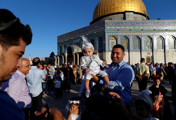 A Palestinian man holds his child who is dressed in festive clothes following morning prayers marking the first day of Eid al-Adha celebrations, on the compound known to Muslims as al-Haram al-Sharif and to Jews as Temple Mount in Jerusalem's Old City September 12, 2016. REUTERS/Ammar Awad