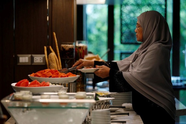 A Muslim visitor takes food from a platter for her breakfast at the Al Meroz hotel in Bangkok, Thailand, August 29, 2016. REUTERS/Chaiwat Subprasom