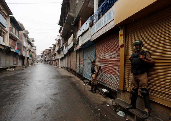 Indian policemen stand guard in front of closed shops during a curfew in Srinagar, July 10, 2016. REUTERS/Danish Ismail