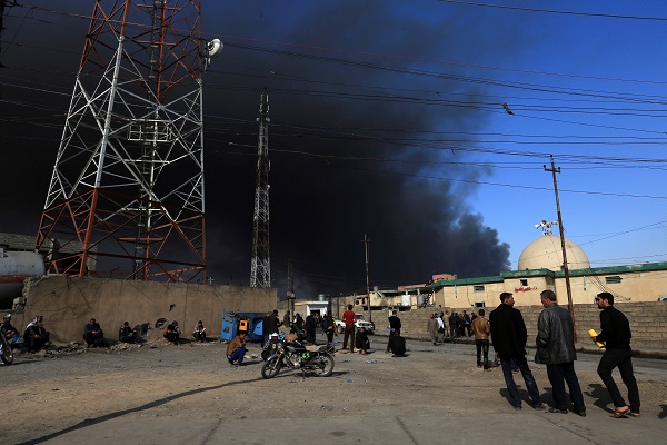 People gather as smoke rises from oil wells, set ablaze by Islamic State militants before the militants fled the oil-producing region of Qayyara, Iraq, November 12, 2016. REUTERS/Ari Jalal